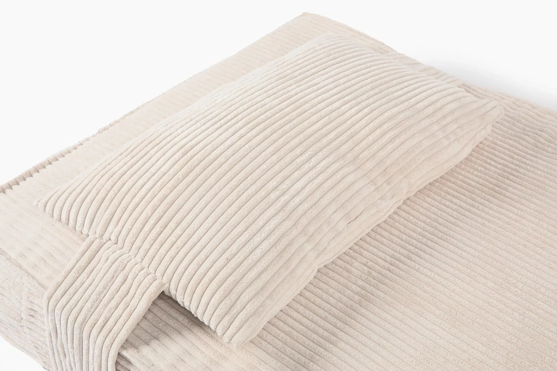 A beige ribbed pillow and covering on a bed with a matching textured pattern.