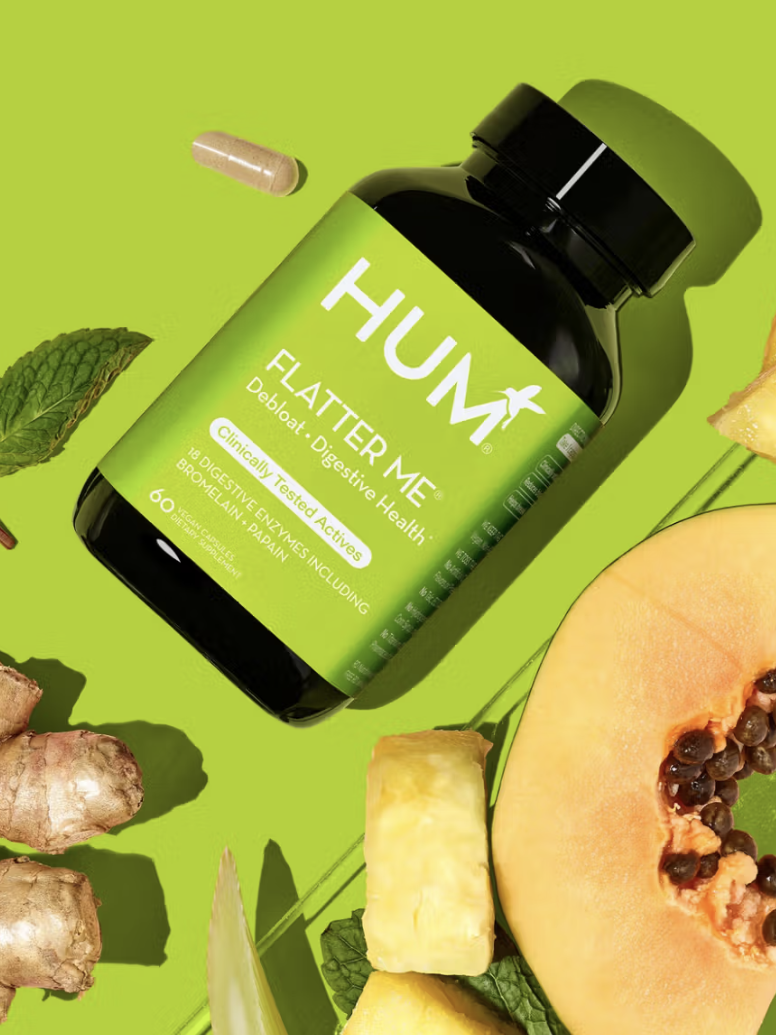 Supplement bottle with capsule, ginger, mint leaves, pineapple, and papaya on a green background.