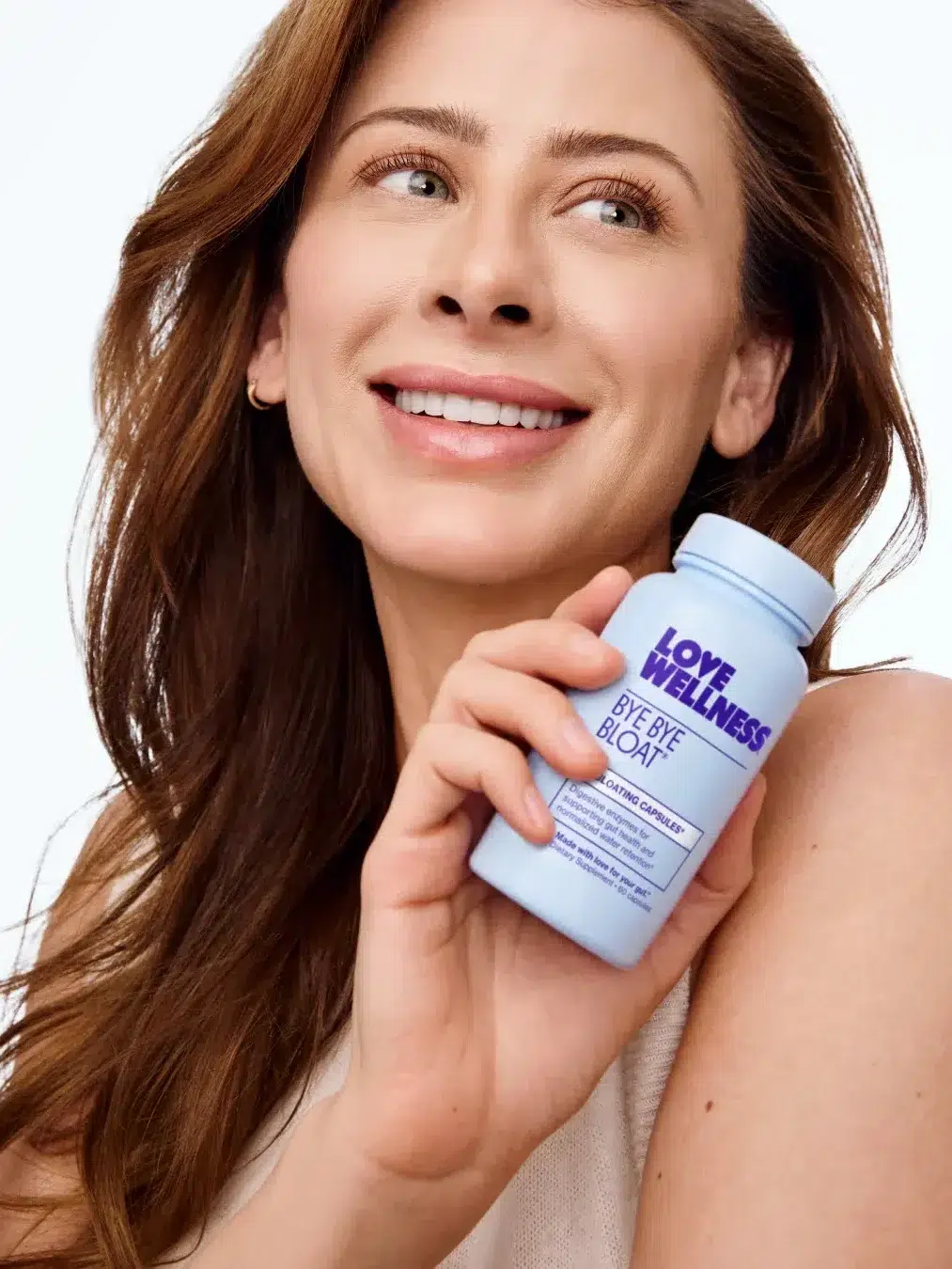 Person smiling and holding a blue bottle labeled "Love Wellness Bye Bye Bloat" against a light background.