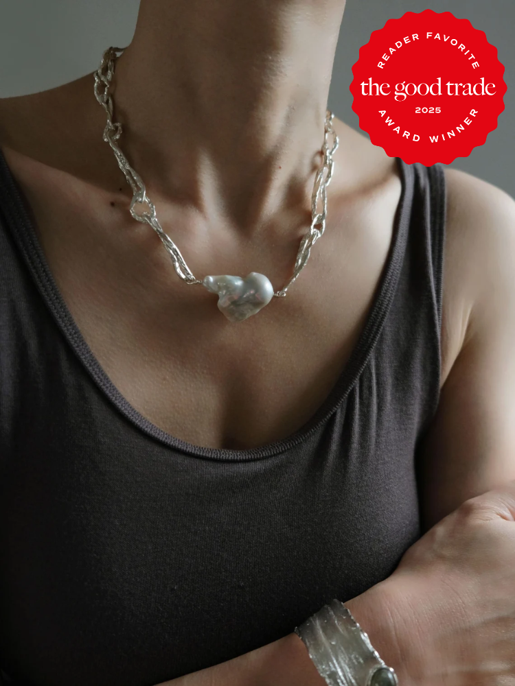 Person wearing a silver chain necklace with a large pearl. They have a dark sleeveless top. A "The Good Trade 2025 Reader Favorite Award Winner" badge is in the top right corner.