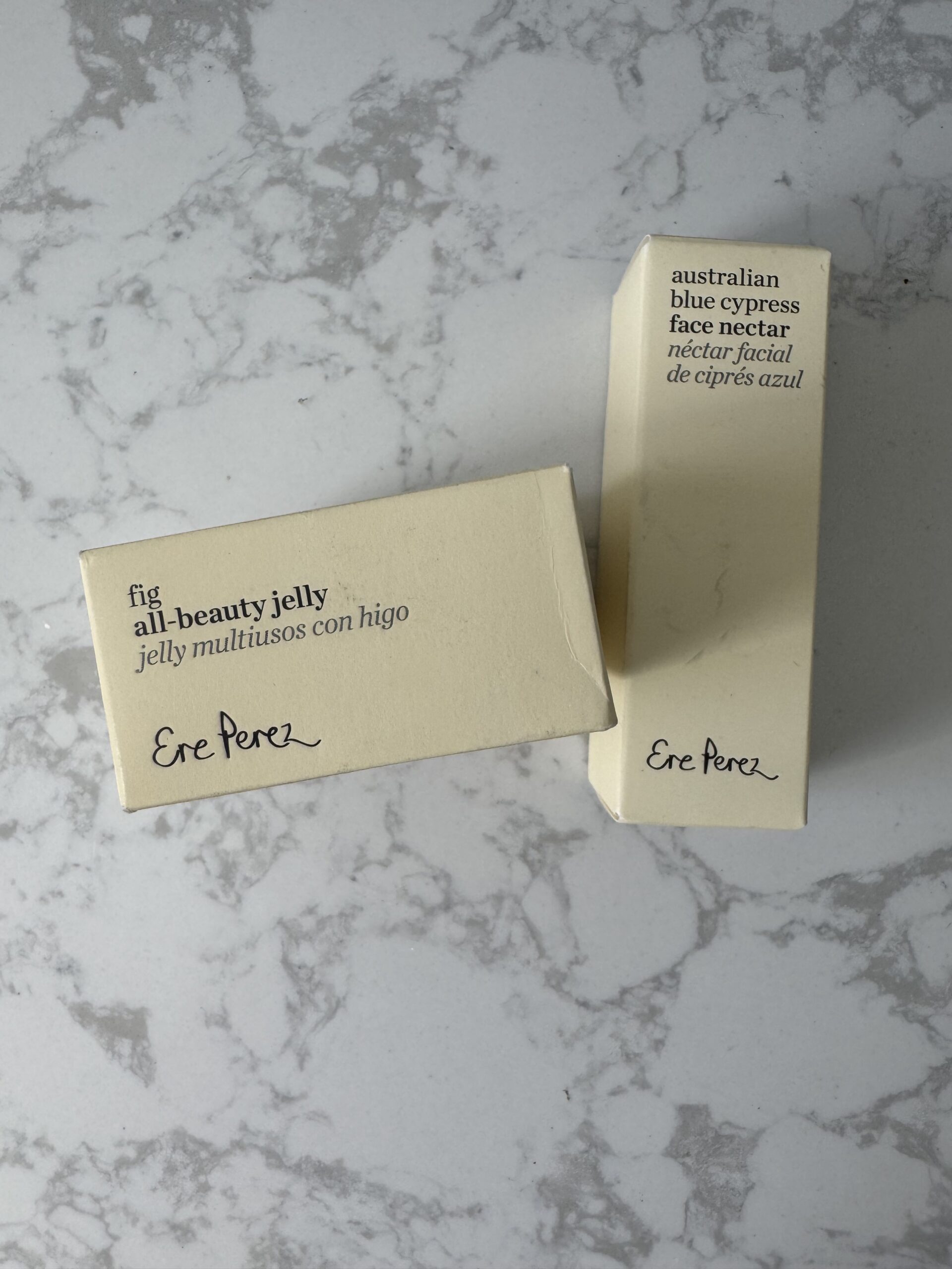 Two small boxes on a marbled surface; one labeled "fig all-beauty jelly," the other "australian blue cypress face nectar." Both have "Ere Perez" in script.