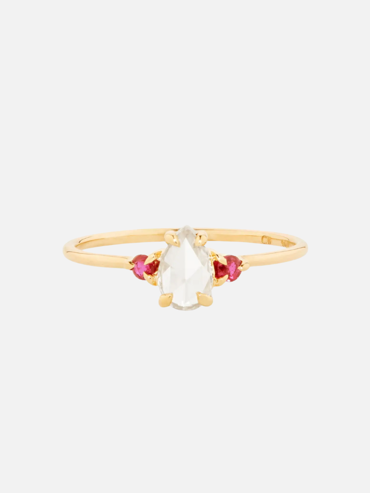 Gold ring featuring a pear-shaped clear gemstone flanked by two small pink stones on each side, set on a thin band.