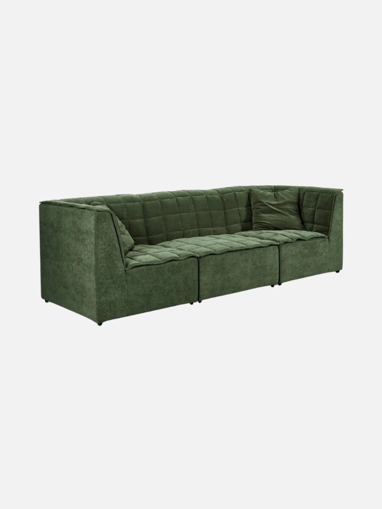 A green, modular sectional sofa with a quilted design and two pillows is placed against a white background.