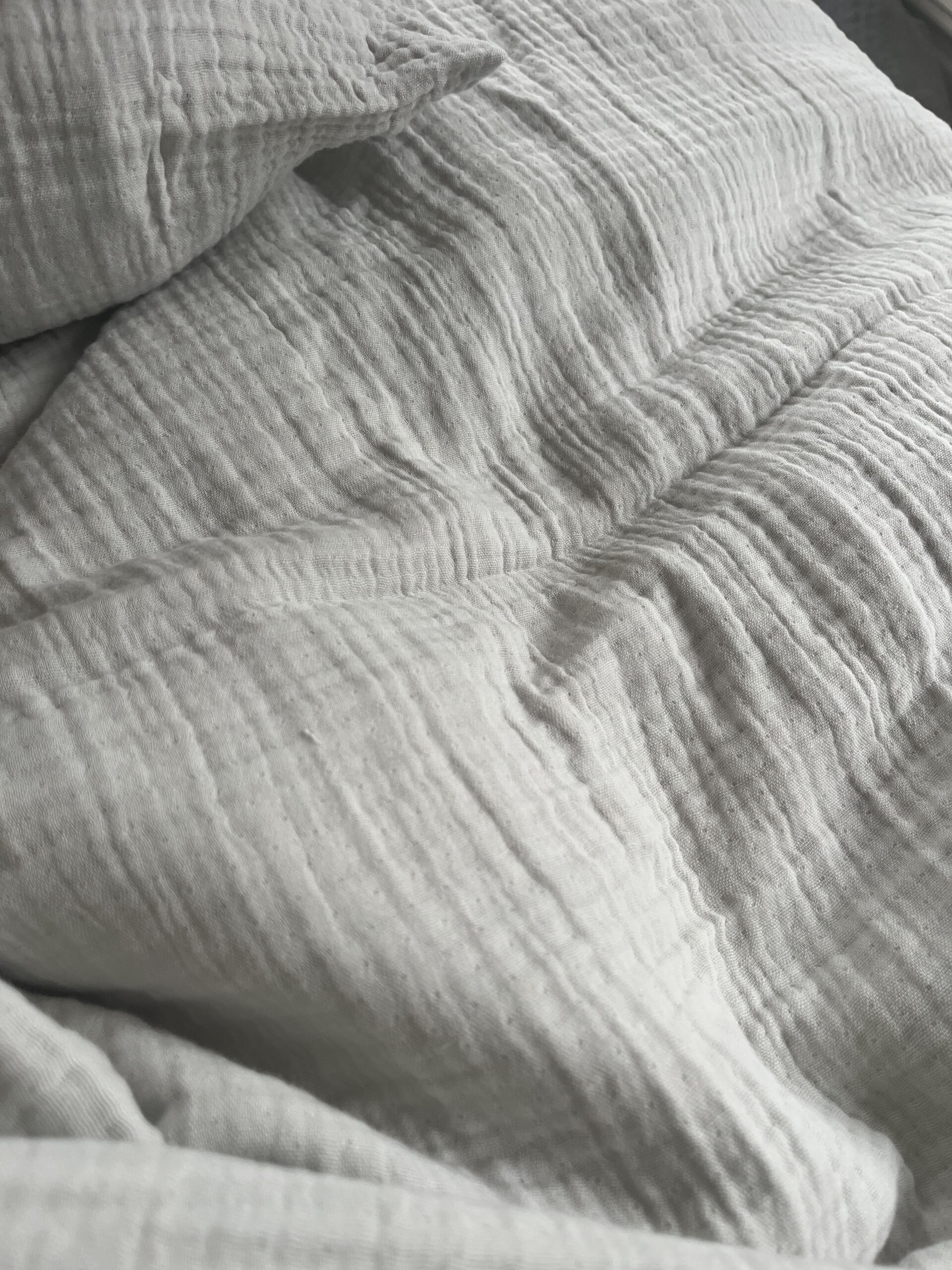 Close-up of crinkled light gray fabric with a soft, textured surface.
