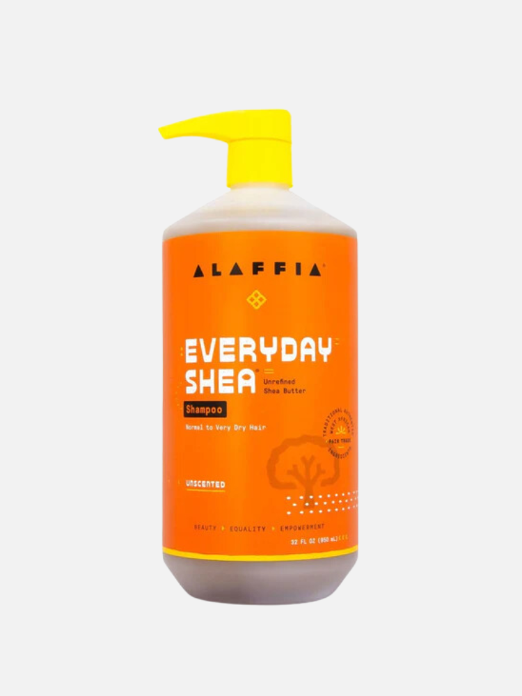 A large bottle of Alaffia Everyday Shea Unscented Shampoo with a yellow pump. The bottle is orange with white and yellow text.