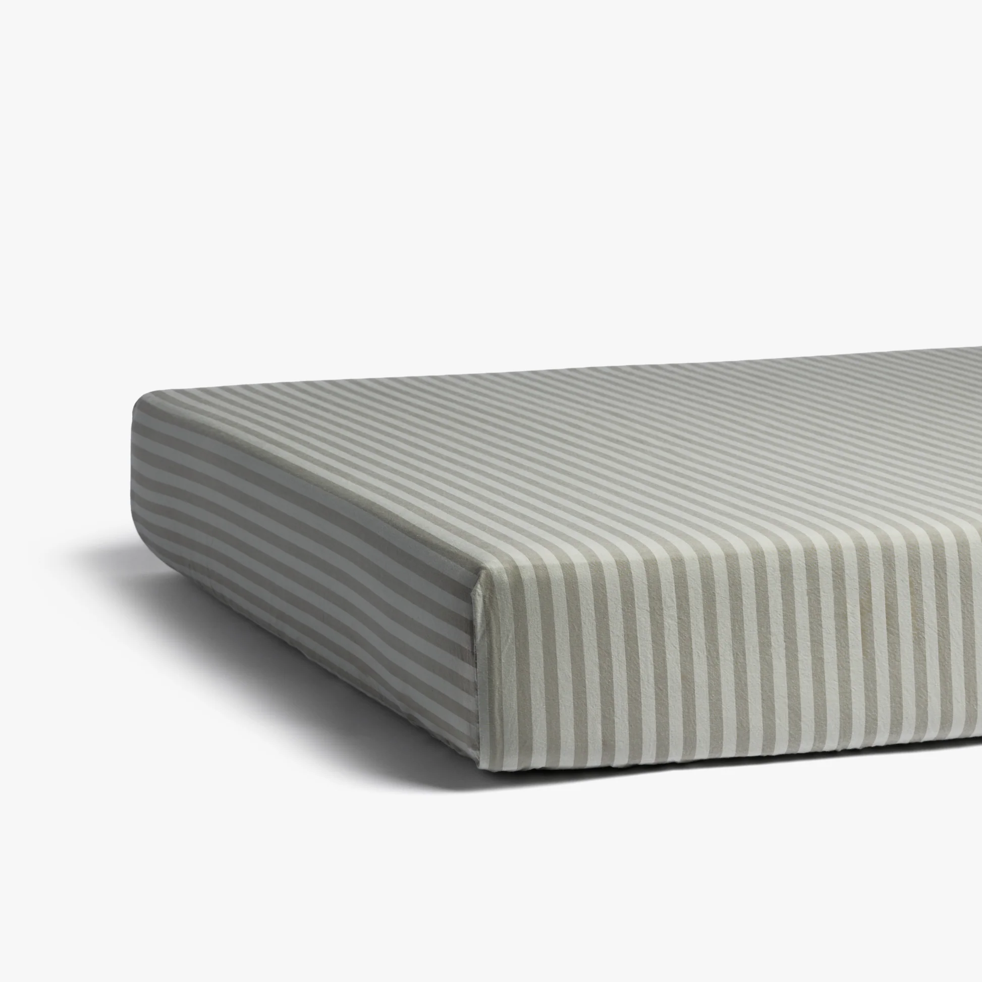 A close-up of a mattress with a fitted sheet featuring horizontal gray and white stripes on a plain white background.