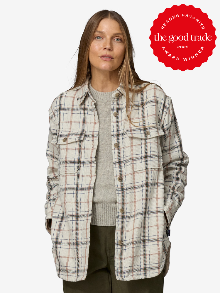 Person wearing a plaid jacket over a grey sweater stands with hands in pockets. A red badge indicating "The Good Trade 2025 Award Winner" is displayed.