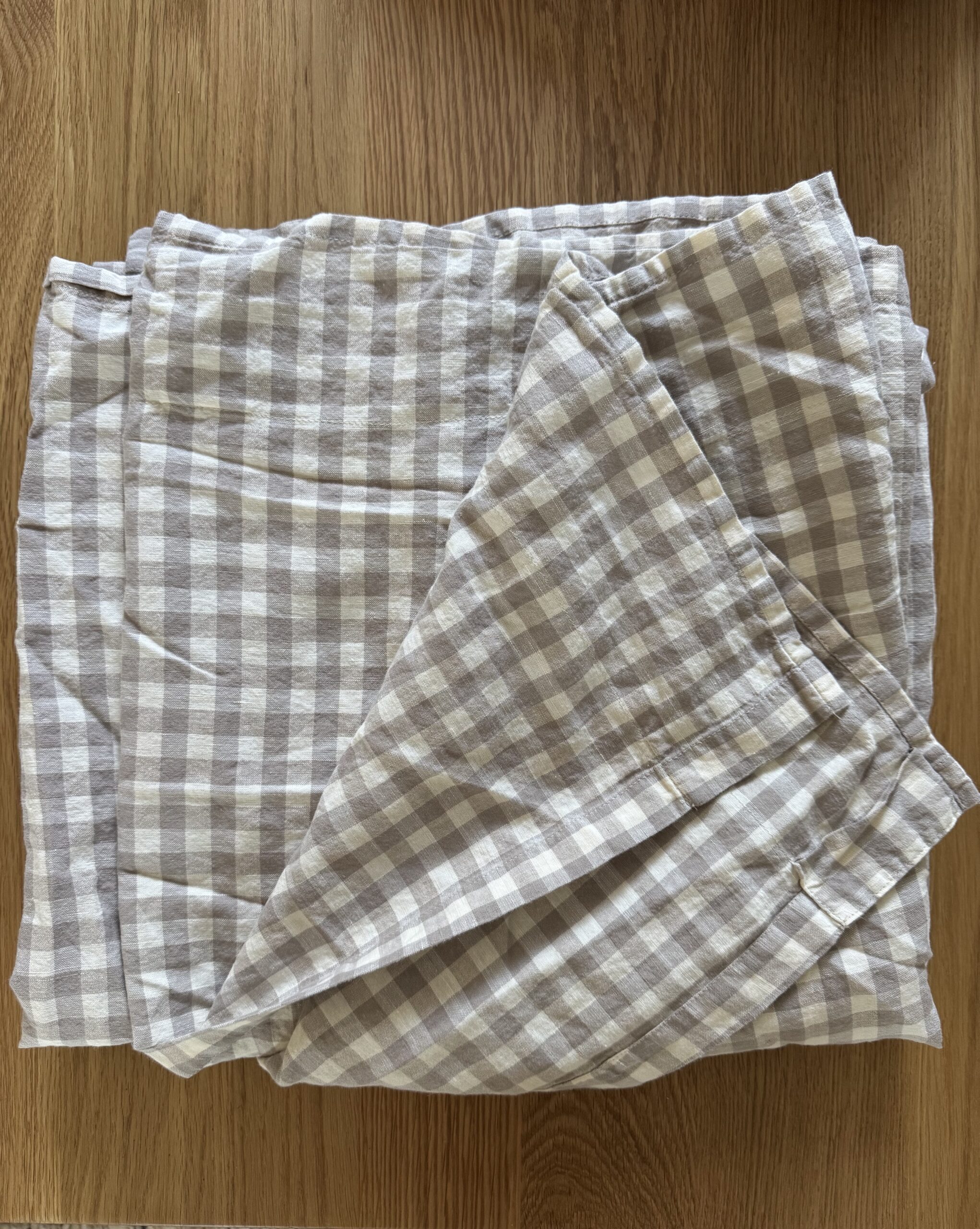 Folded beige and white checkered cloth napkins sit on a wooden surface.
