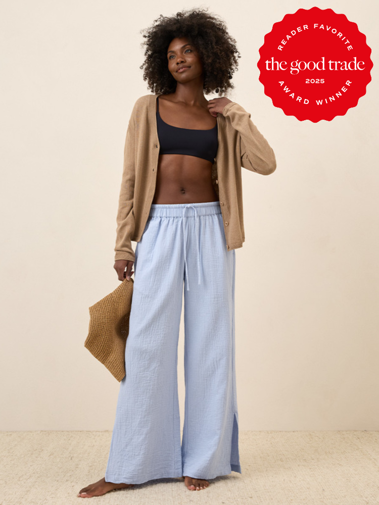 Woman wearing a black top, beige cardigan, and light blue pants holds a hat. The Good Trade 2023 Reader Favorite Award logo is in the corner.