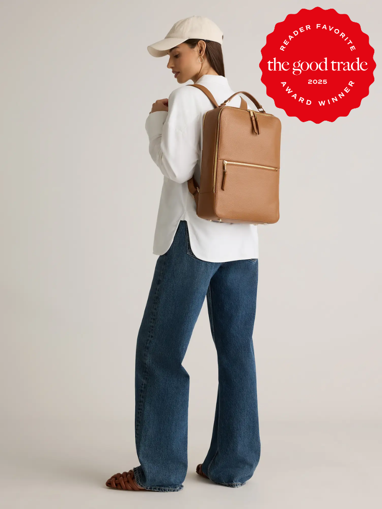 A person wearing a white shirt, blue jeans, and a beige cap carries a tan backpack. A red badge in the corner reads, "The Good Trade Award Winner 2023.