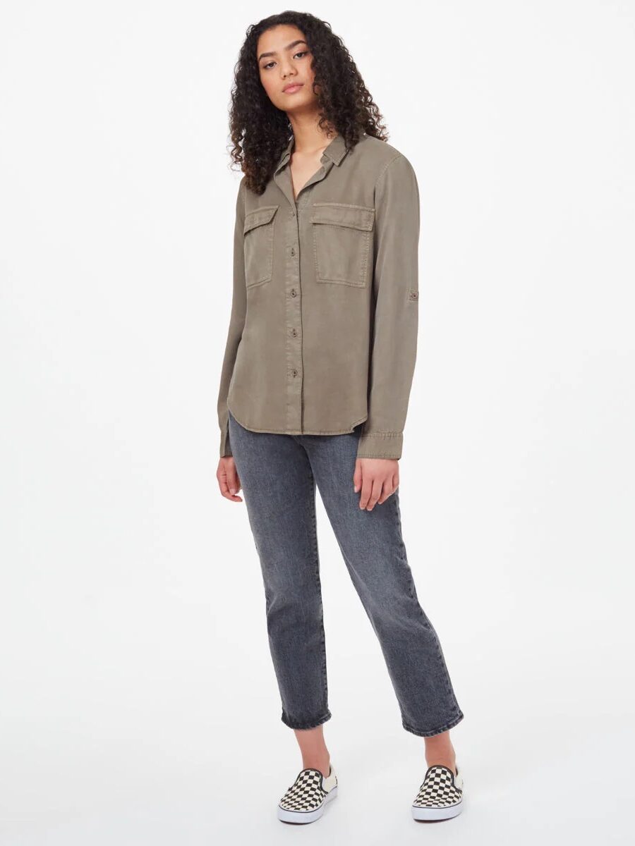 Person wearing a khaki button-up shirt, gray jeans, and checkered shoes, standing against a plain white background.