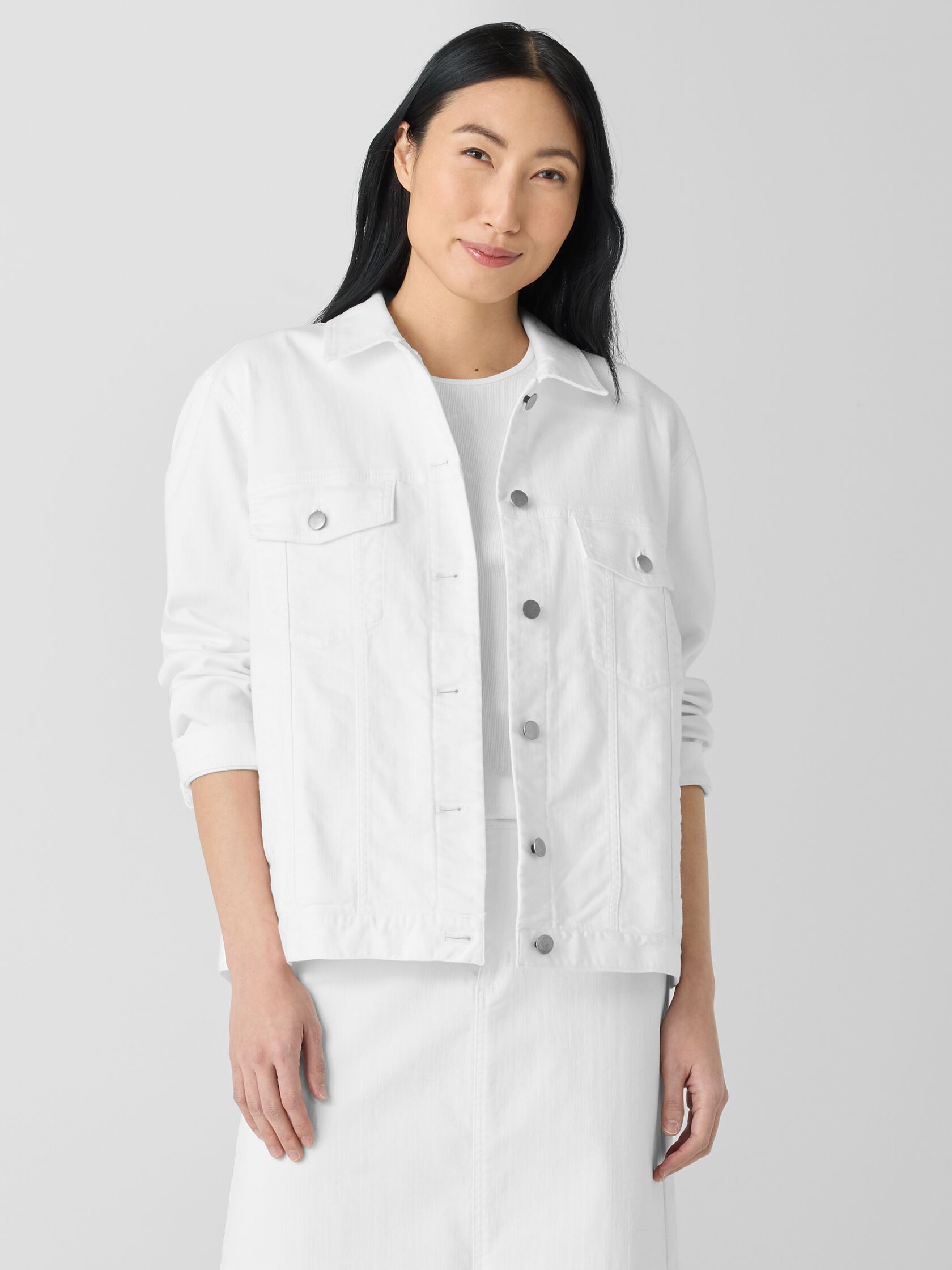 Person wearing a white denim jacket and skirt, standing in front of a plain white background.