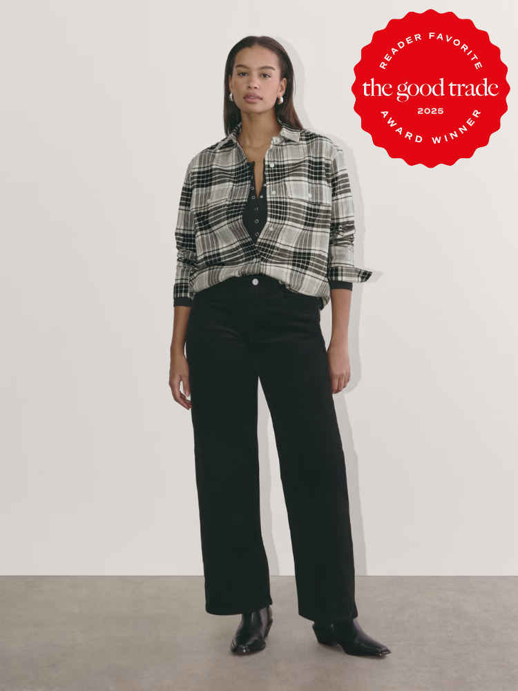 A person wearing a black and white plaid shirt, black pants, and black shoes stands against a light background. A "The Good Trade 2023 Reader Favorite Award Winner" badge is in the top right corner.