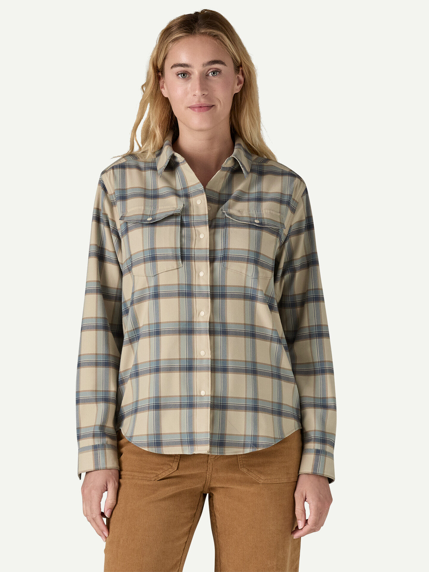 Person wearing a beige and blue plaid button-up shirt stands against a plain background.