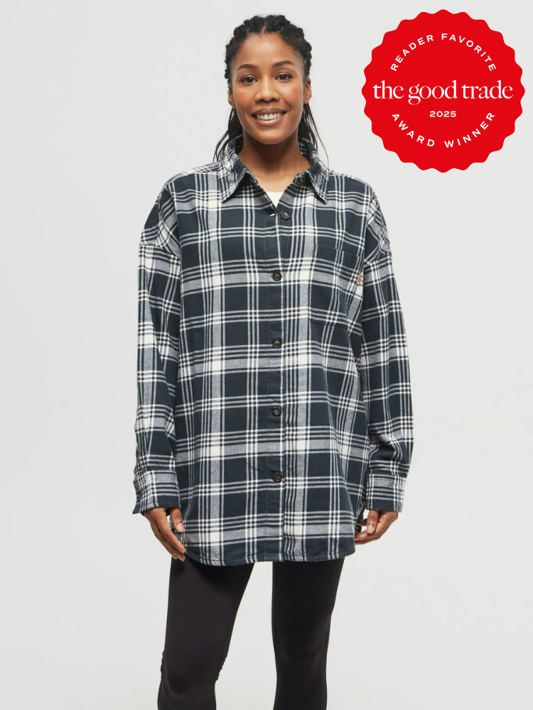 Person in a black and white plaid shirt and black leggings stands smiling. A red badge reads "Reader Favorite, The Good Trade, Award Winner, 2023" in the upper right corner.