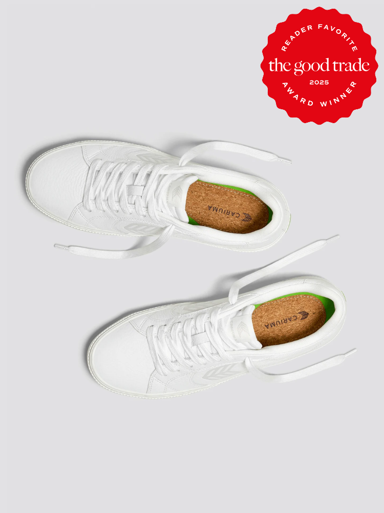 White Cariuma sneakers on a gray background with a red "The Good Trade Reader Favorite Award Winner 2025" badge in the corner.