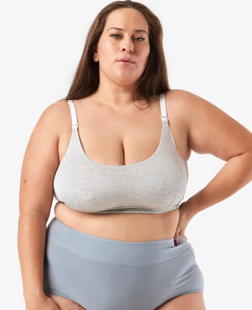 Person wearing a light gray sports bra and high-waisted blue underwear, posing against a white background.