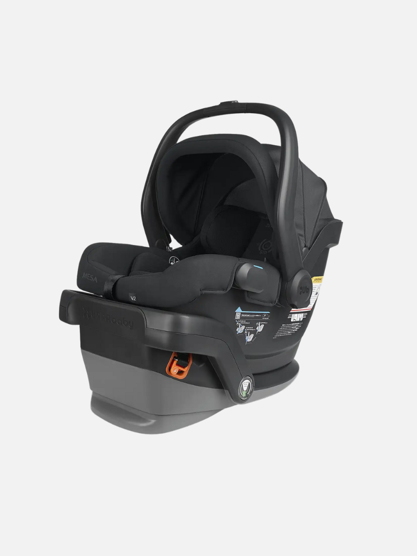 Black infant car seat with a carrying handle on a gray base, featuring safety instruction labels and harness system.