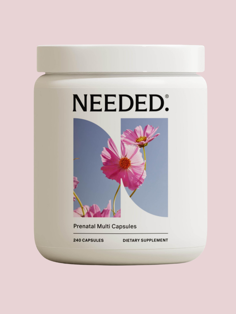 A white container labeled "Needed Prenatal Multi Capsules" with an image of pink flowers, set against a light pink background. Contains 240 capsules.