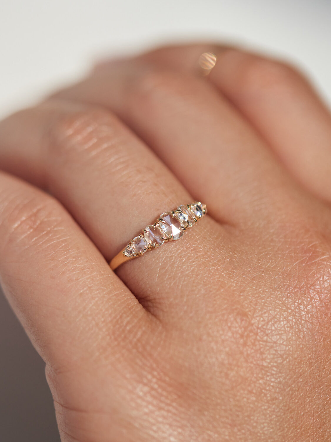 A gold ring with multiple gemstones is worn on a person's hand.