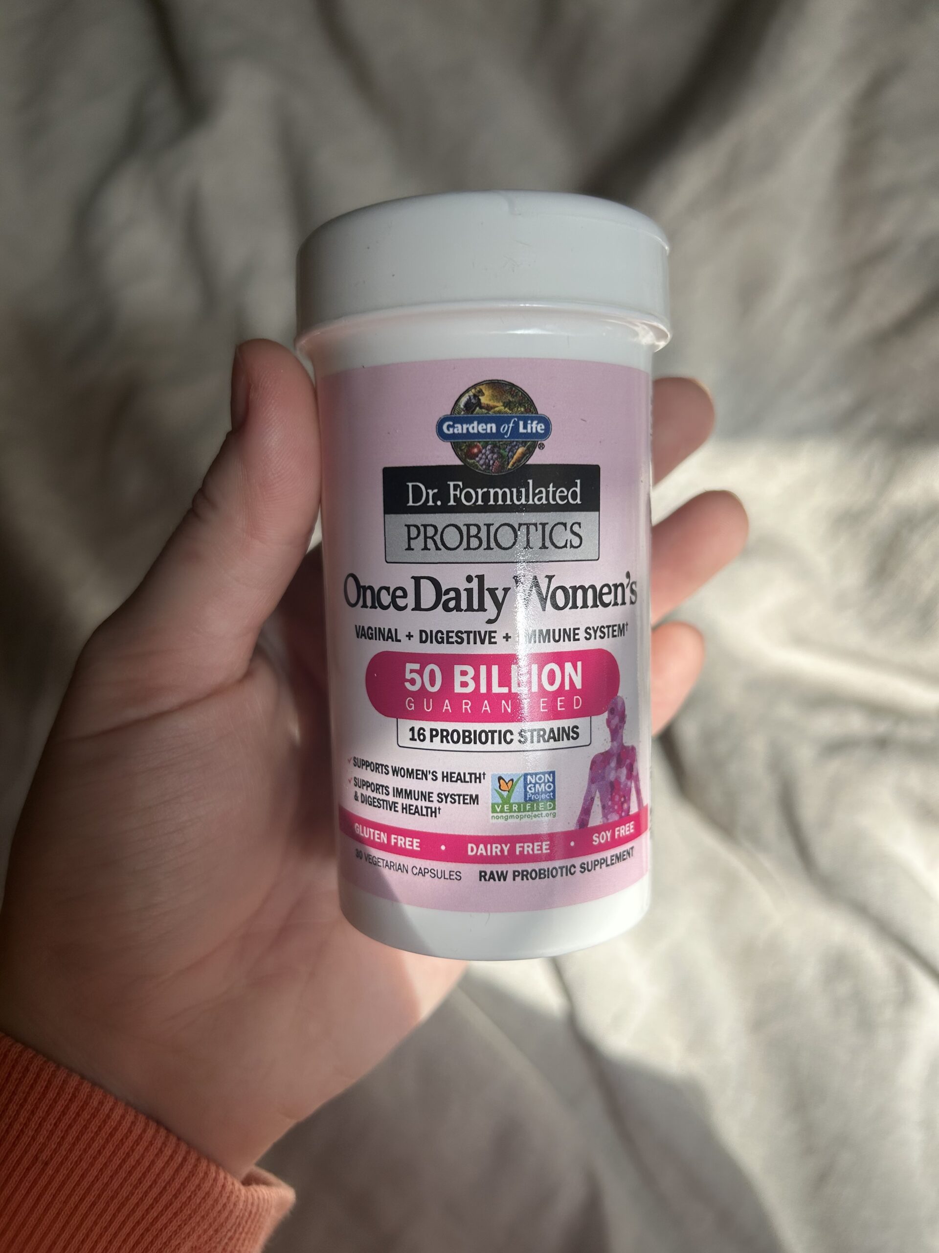 A hand holds a container of Dr. Formulated Probiotics Once Daily Women’s, 50 billion CFU, by Garden of Life.