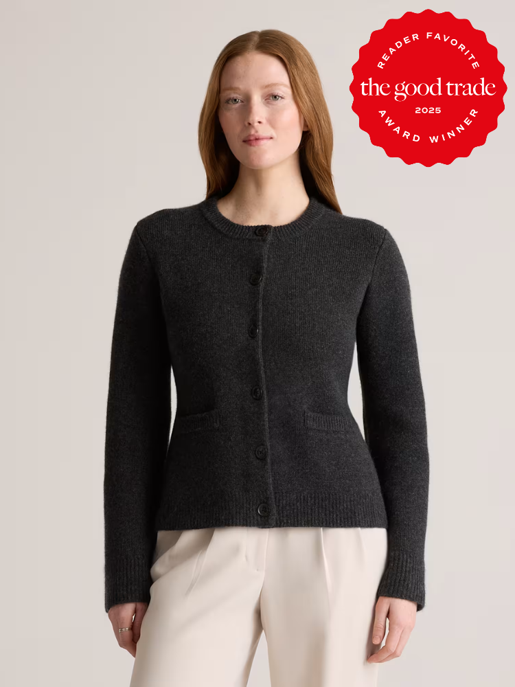 Person wearing a dark cardigan and light pants, standing in front of a neutral background. A "The Good Trade" award badge is displayed in the top right corner.