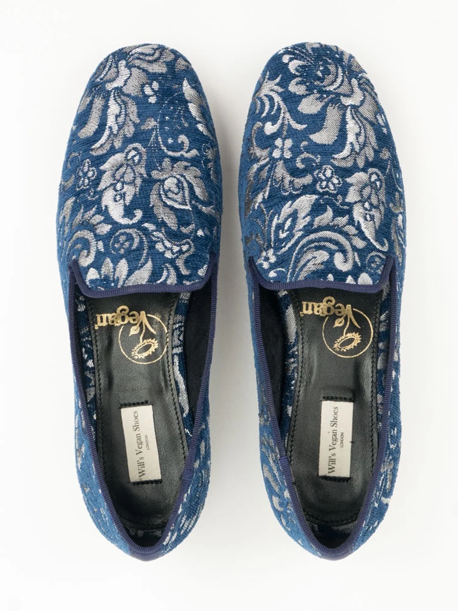 Blue embroidered loafers with silver floral pattern, top view, on a white background.