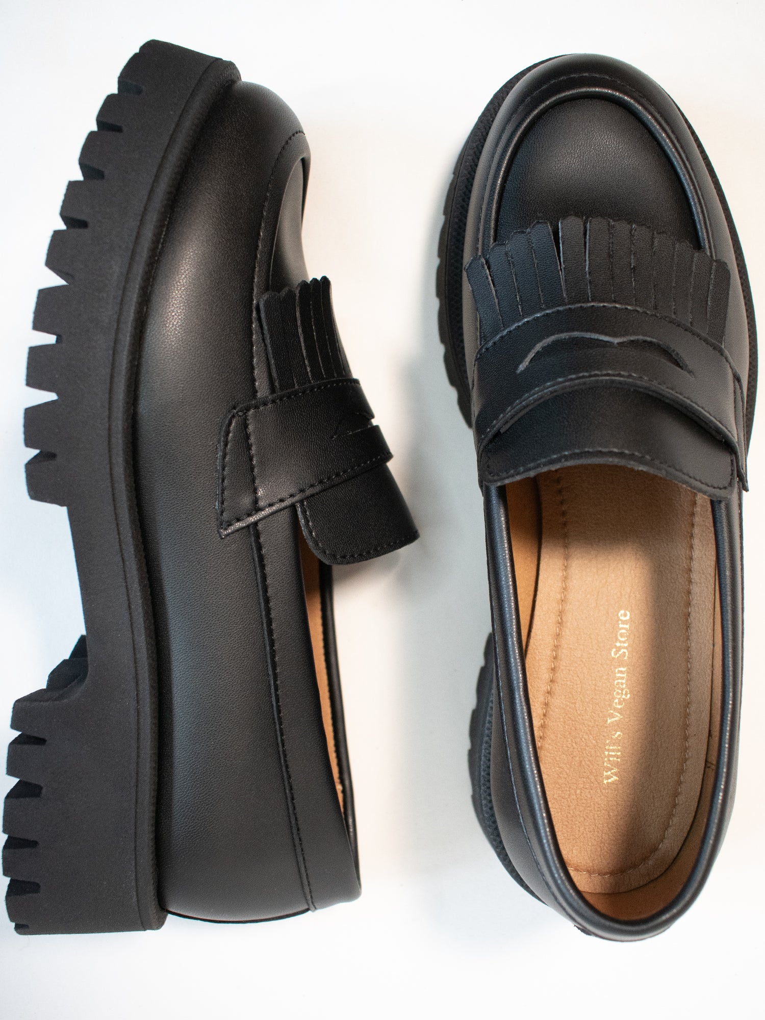 Black platform loafers with chunky soles and fringe details, viewed from the side and top. Insole reads "Viva Vegan Store.