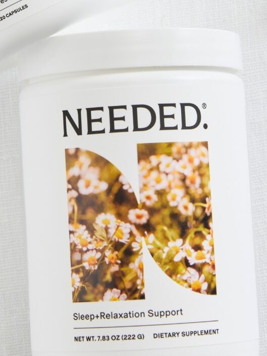 Two white containers labeled "NEEDED" for dietary supplements, surrounded by small white flowers.