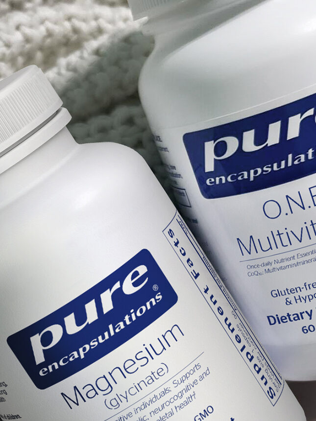 Two bottles of dietary supplements on a knitted blanket. One bottle is Magnesium Glycinate, the other is O.N.E. Multivitamin. A note reads: "Autumn Savings on all Supplements*.