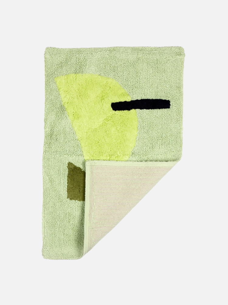 A green textured rug with abstract shapes in yellow and black, partially folded at one corner.