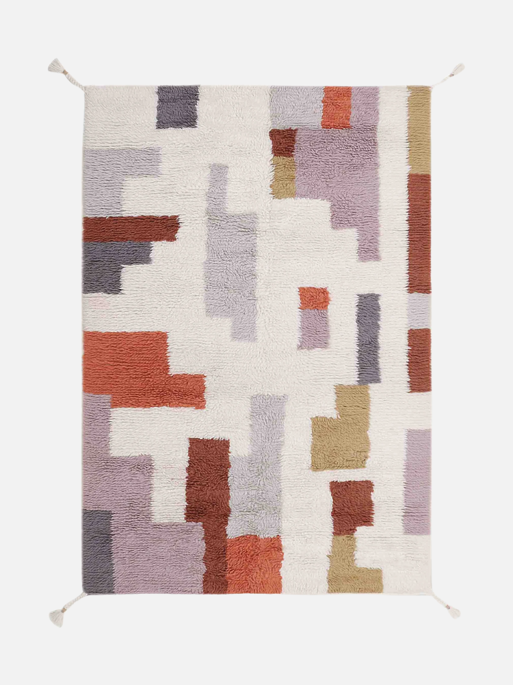 Rectangular rug with an abstract geometric pattern in shades of red, purple, and beige on a white background.