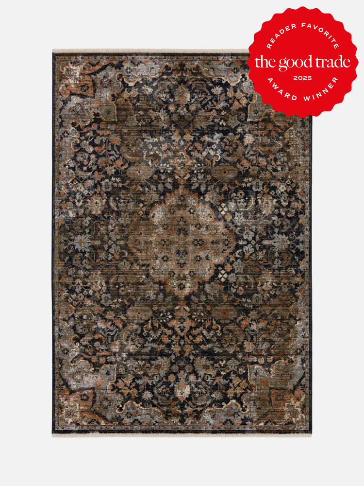 A rectangular, vintage-style rug with a central medallion pattern in dark and muted tones. It features a red "Reader Favorite: The Good Trade 2023 Award Winner" badge in the upper right corner.