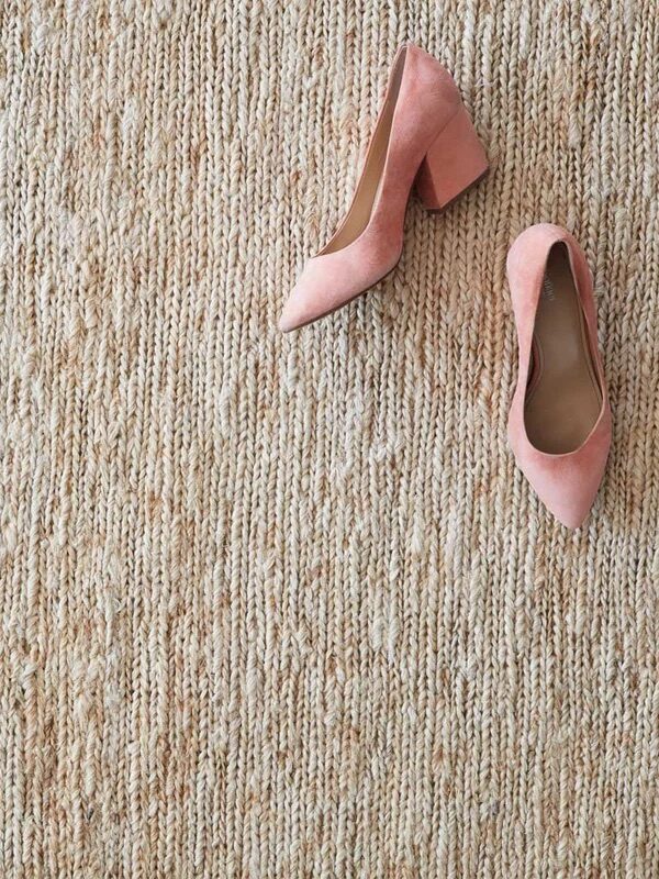 A pair of pink high-heeled shoes placed on a textured beige carpet.