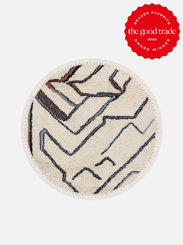 Round beige rug with abstract black and brown lines on a white background. Red badge in the top right corner reads: "Reader Favorite, The Good Trade, Award Winner 2025.