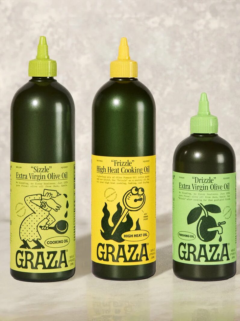 Three bottles of Graza olive oil in varying sizes are displayed against a neutral background. Labels read: "Sizzle" Cooking Oil, "Frizzle" High Heat Cooking Oil, and "Drizzle" Extra Virgin Olive Oil.