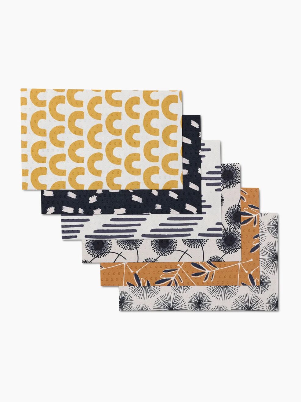 Five rectangular fabric pieces with different patterns: yellow geometric shapes, black and white abstract designs, and orange with plant motifs.
