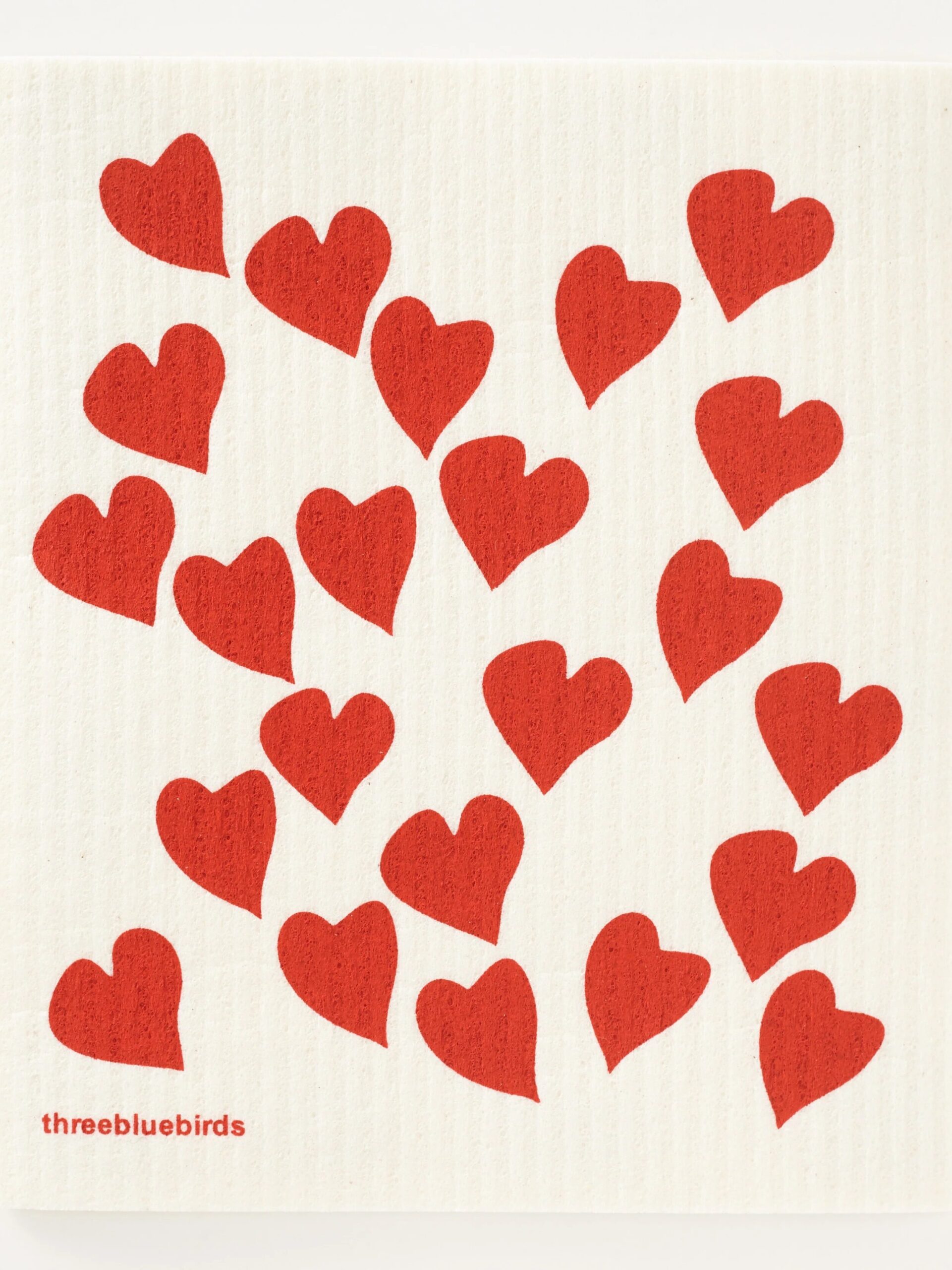 White cloth with a pattern of scattered red hearts and a small "threebluebirds" logo in the corner.