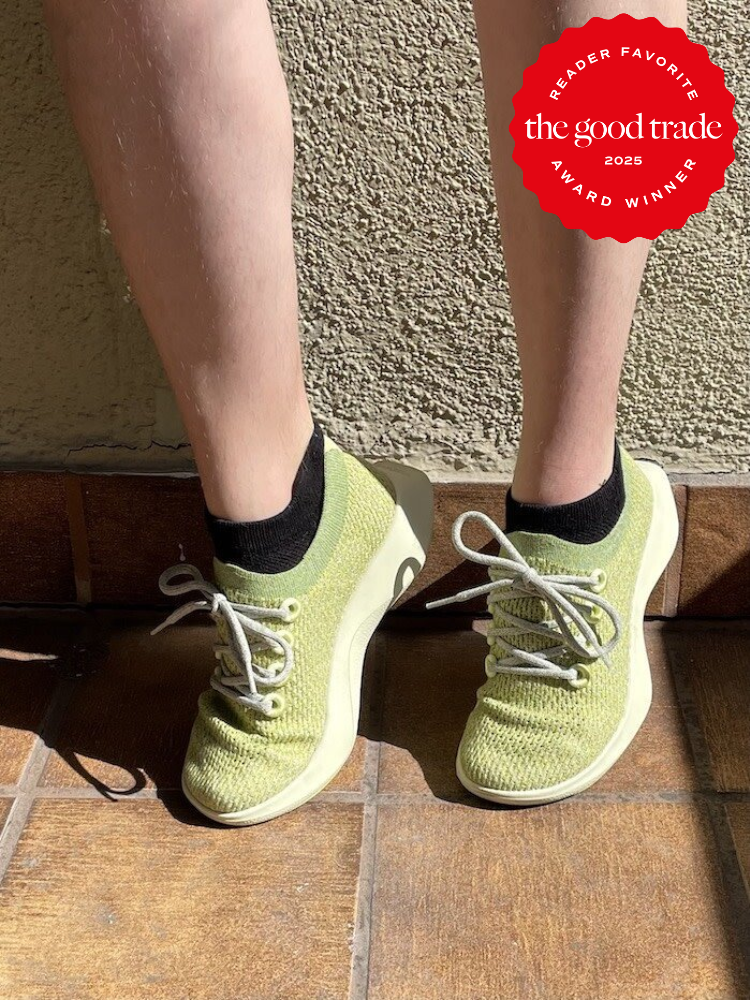 Person wearing green sneakers with black socks on a tiled floor; a "Reader Favorite the good trade 2025 Award Winner" badge is in the top right corner.