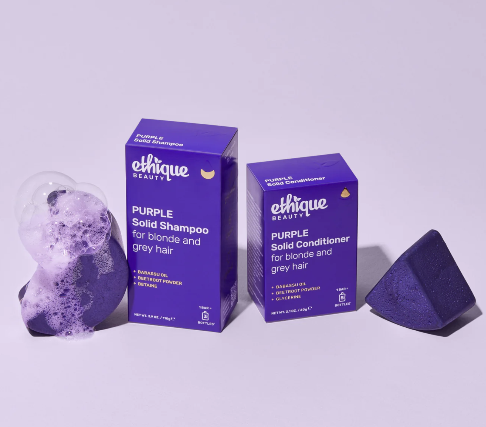 Ethique Beauty purple solid shampoo and conditioner bars with packaging, designed for blonde and grey hair. The shampoo is lathered with bubbles.