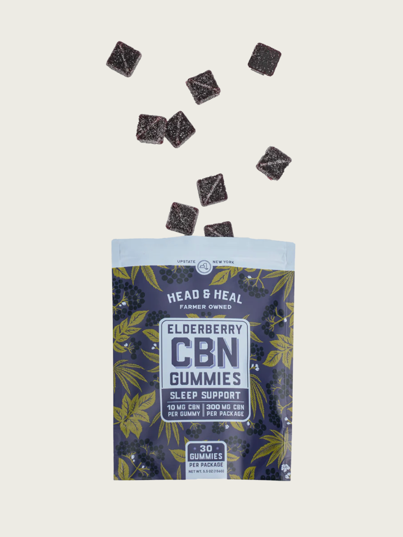 A package of Head & Heal Elderberry CBN Gummies with several gummies falling above the open bag. The label highlights sleep support and contains 30 gummies per package.