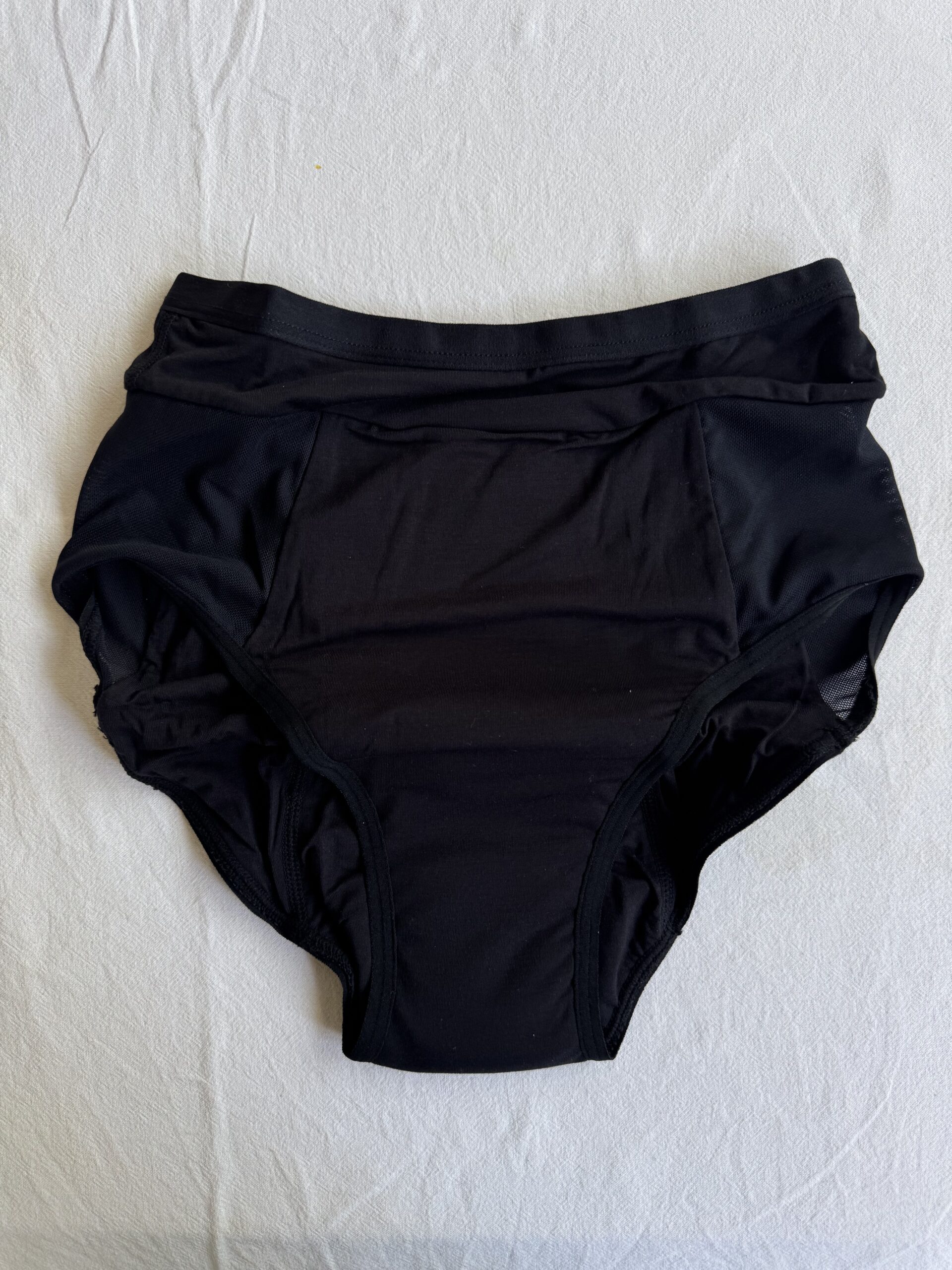 Black high-waisted underwear on a white surface, featuring a simple design with subtle seams and a plain texture.