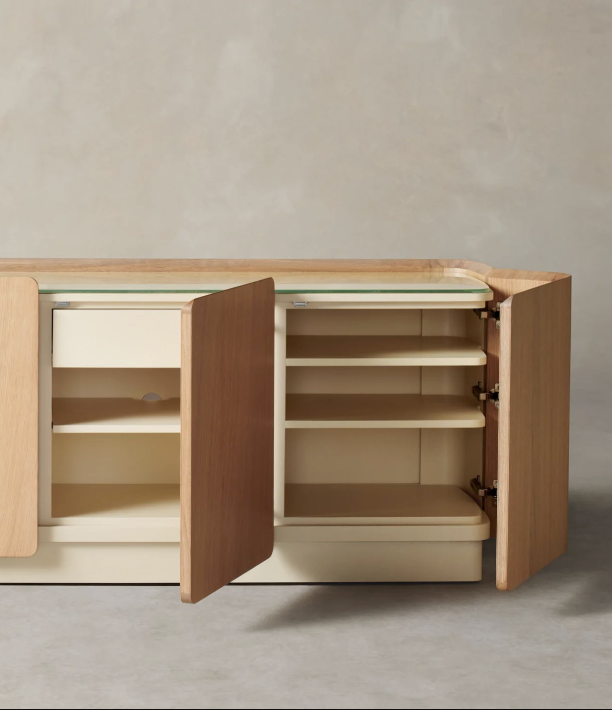 A wooden sideboard with three cabinet doors open, revealing shelves and interior storage compartments against a neutral background.