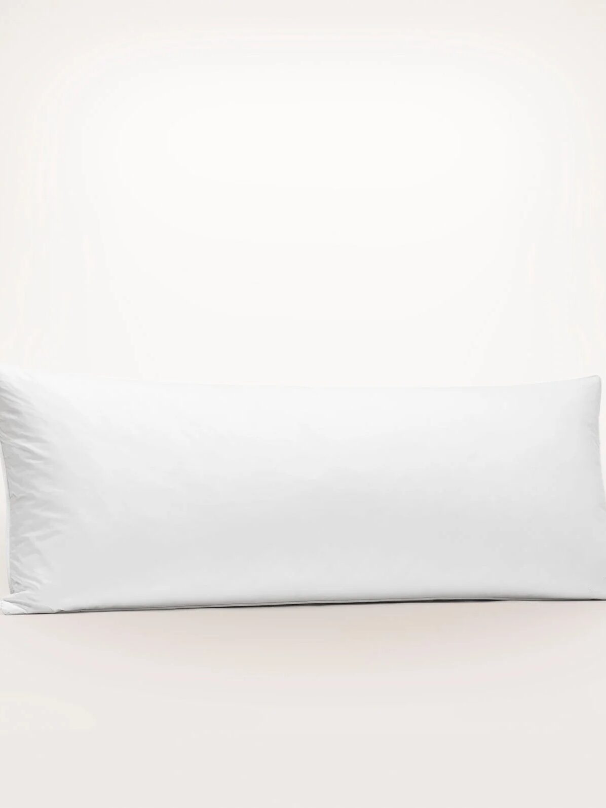 A standard white rectangular pillow with a smooth surface, set against a plain light background.