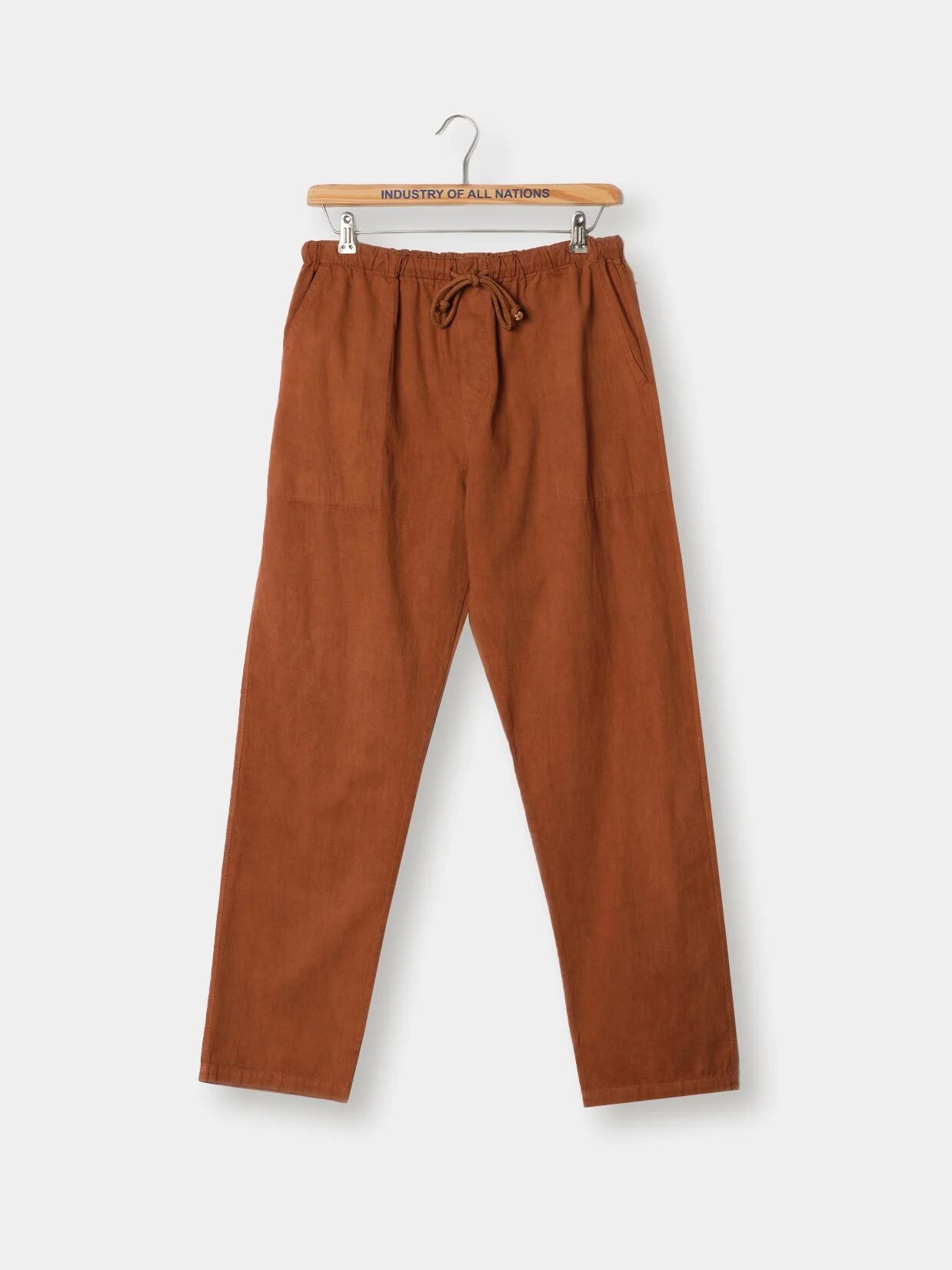 Brown pants with an elastic waistband and a drawstring, hanging on a wooden hanger against a plain white background.