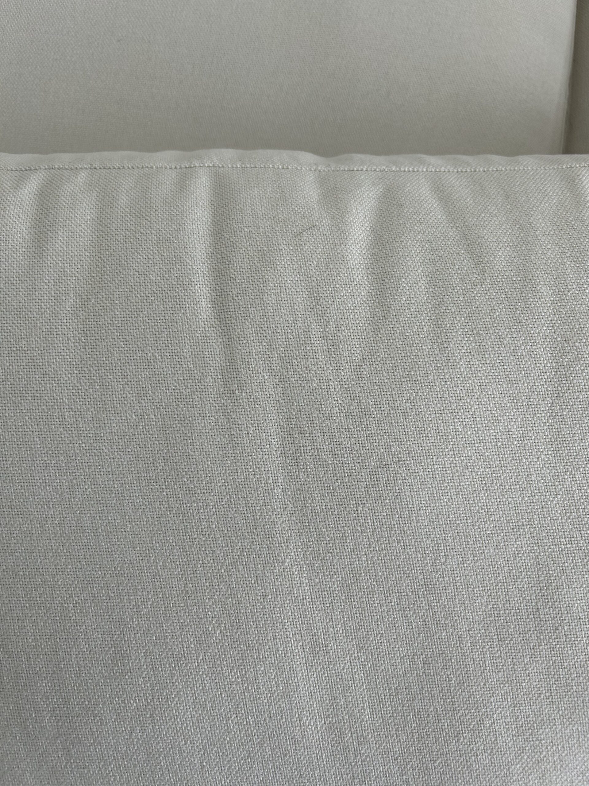 Close-up of two light gray fabric cushions with visible stitching and slight wrinkles on the surface.