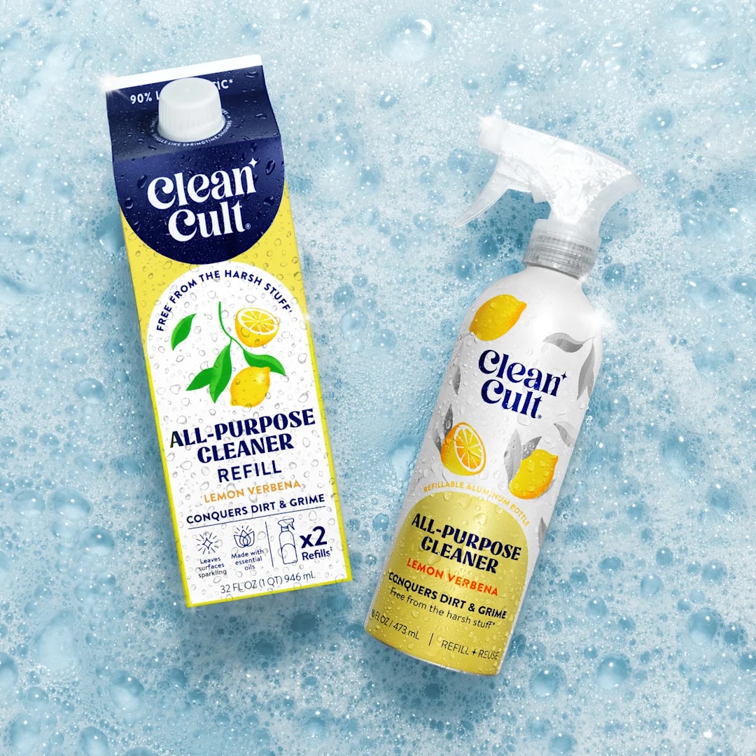 A refill carton and spray bottle of Clean Cult All-Purpose Cleaner in Lemon Verbena scent are placed on a soapy, blue surface.