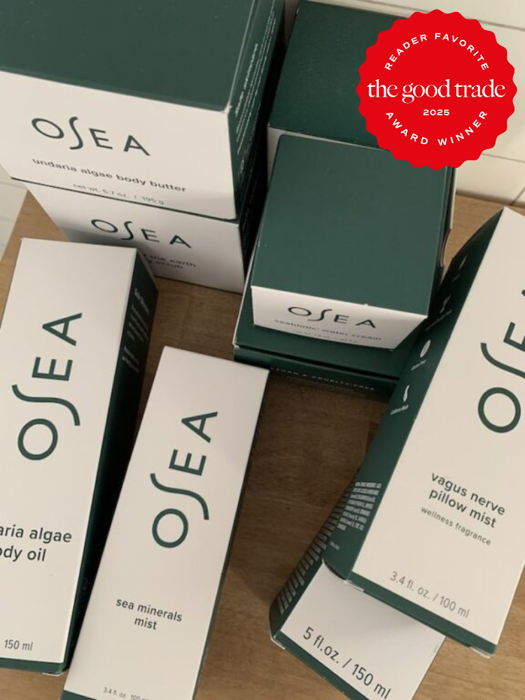 OSEA skincare products, including body butter, body oil, and mists, are arranged on a wooden surface. A red badge in the corner reads "The Good Trade Award Winner 2023, Reader Favorite.