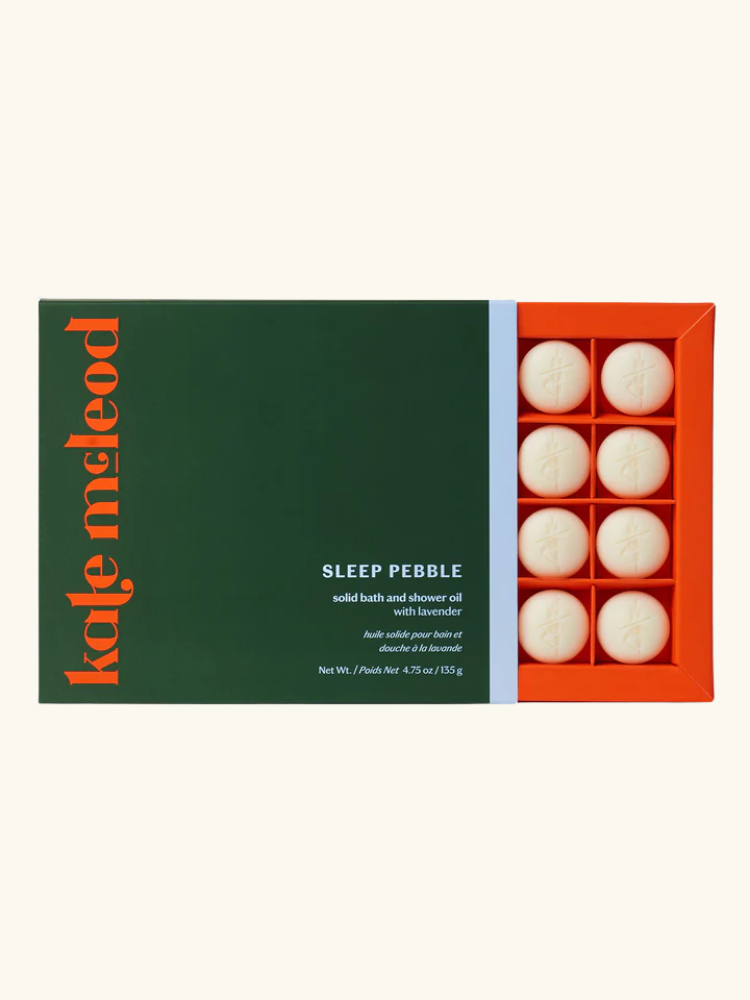 A green and orange box labeled "kate mcleod" contains eight round white solid bath and shower oil pebbles called "Sleep Pebble" with lavender.