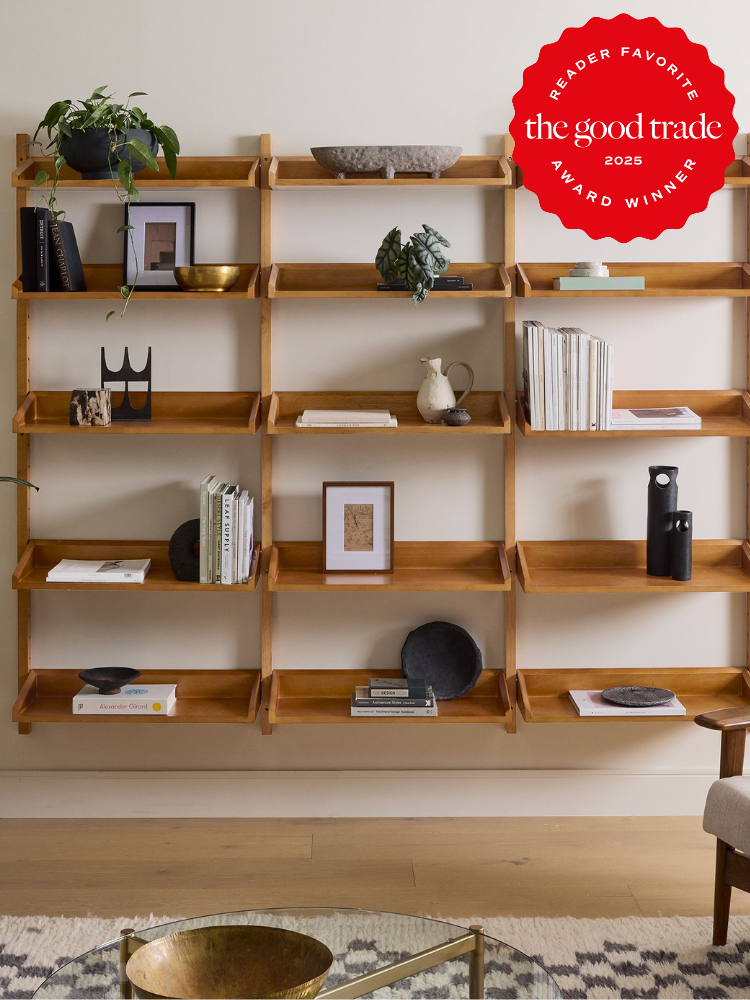 A wooden wall-mounted bookshelf displays books, decorative objects, and plants; a “The Good Trade Award Winner 2025” badge is in the top right corner.